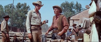Movie still from “The Magnificent Seven” (1960), directed by John Sturges – Two men in cowboy hats are standing next to each other; Medium shot, Low angle