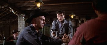 Movie still from “The Magnificent Seven” (1960), directed by John Sturges – A man holding a gun while standing next to another man holding a gun; Medium shot, Over the shoulder angle