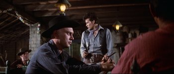Movie still from “The Magnificent Seven” (1960), directed by John Sturges – Two men in cowboy hats are smoking a cigar; Medium shot, Over the shoulder angle