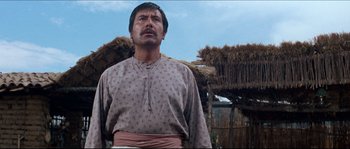 Movie still from “The Magnificent Seven” (1960), directed by John Sturges – A man standing in front of a straw hut; Medium shot, Low angle