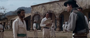 Movie still from “The Magnificent Seven” (1960), directed by John Sturges – A group of men standing in front of an old building; Wide shot, Low angle