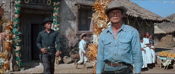 Movie still from “The Magnificent Seven” (1960), directed by John Sturges – A man in a cowboy hat standing in front of a building; Medium shot, Low angle