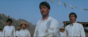 Movie still from “The Magnificent Seven” (1960), directed by John Sturges – A man in a white shirt standing in front of a group of men; Medium shot, Low angle