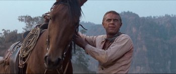 Movie still from “The Magnificent Seven” (1960), directed by John Sturges – A man standing next to a horse on a field; Close Up shot, Low angle