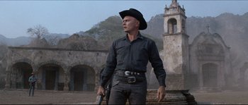 Movie still from “The Magnificent Seven” (1960), directed by John Sturges – A man wearing a cowboy hat and holding a gun; Medium shot, Low angle
