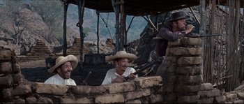 Movie still from “The Magnificent Seven” (1960), directed by John Sturges – A group of men sitting next to each other on top of a hill; Medium shot, Low angle