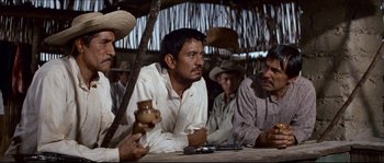 Movie still from “The Magnificent Seven” (1960), directed by John Sturges – A group of men sitting around a wooden table; Medium shot, Over the shoulder angle