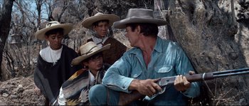 Movie still from “The Magnificent Seven” (1960), directed by John Sturges – A group of men sitting next to each other on the ground; Medium shot, Over the shoulder angle