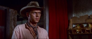 Movie still from “The Magnificent Seven” (1960), directed by John Sturges – A man wearing a cowboy hat standing in front of a red curtain; Close Up shot, Over the shoulder angle