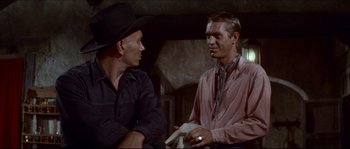 Movie still from “The Magnificent Seven” (1960), directed by John Sturges – Two men in cowboy hats talking to each other; Medium shot, Over the shoulder angle