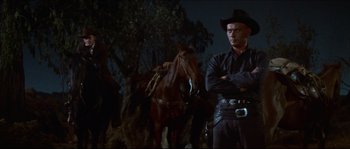 Movie still from “The Magnificent Seven” (1960), directed by John Sturges – A man standing next to a horse in the dark; Medium shot, Low angle