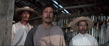 Movie still from “The Magnificent Seven” (1960), directed by John Sturges – A group of men standing next to each other in a barn; Medium shot, Low angle