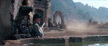 Movie still from “The Magnificent Seven” (1960), directed by John Sturges – A man sitting on the ground holding a gun in his hands; Wide shot, Low angle