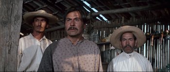 Movie still from “The Magnificent Seven” (1960), directed by John Sturges – A man with a mustache standing next to two other men; Medium shot, Low angle