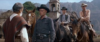 Movie still from “The Magnificent Seven” (1960), directed by John Sturges – Two men in cowboy hats are riding horses; Medium shot, Low angle