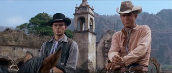 Movie still from “The Magnificent Seven” (1960), directed by John Sturges – Two men in cowboy hats are sitting on horses in front of an old church; Medium shot, Low angle