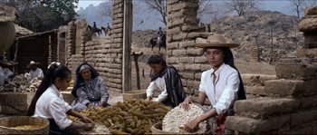 Movie still from “The Magnificent Seven” (1960), directed by John Sturges – A group of people standing next to a pile of food; Medium shot, Low angle