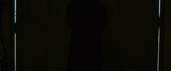 Movie still from “The Maid” (2020), directed by Lee Thongkham – A person standing in the dark with their arms crossed; Medium shot, Low angle