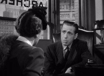 Movie still from “The Maltese Falcon” (1941), directed by John Huston – A man and a woman sitting at a table in front of each other; Close Up shot, Over the shoulder angle