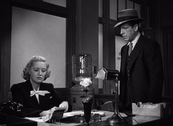 Movie still from “The Maltese Falcon” (1941), directed by John Huston – A man and a woman sitting at a table; Medium shot, Low angle