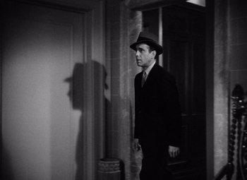 Movie still from “The Maltese Falcon” (1941), directed by John Huston – A black and white photo of a man in a suit and hat; Medium shot, Low angle