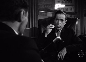 Movie still from “The Maltese Falcon” (1941), directed by John Huston – A man sitting in a chair talking to another man in a suit; Close Up shot, Over the shoulder angle