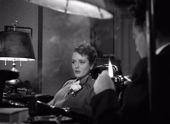 Movie still from “The Maltese Falcon” (1941), directed by John Huston – A woman sitting in front of a mirror in front of a camera; Medium shot, High angle