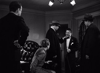 Movie still from “The Maltese Falcon” (1941), directed by John Huston – A group of people standing in a living room talking; Medium shot, Over the shoulder angle