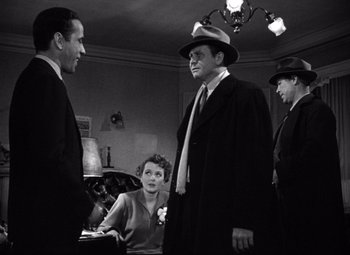 Movie still from “The Maltese Falcon” (1941), directed by John Huston – A group of men standing around a woman in a room; Medium shot, Over the shoulder angle