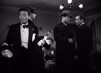 Movie still from “The Maltese Falcon” (1941), directed by John Huston – A black and white photo of a group of men in suits and hats; Medium shot, Low angle