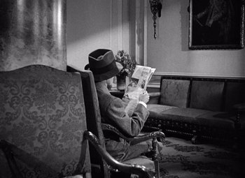 Movie still from “The Maltese Falcon” (1941), directed by John Huston – An older man sitting in a chair reading a newspaper; Medium shot, High angle