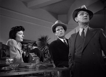 Movie still from “The Maltese Falcon” (1941), directed by John Huston – A group of men and women standing around a table; Medium shot, Low angle
