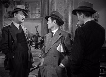 Movie still from “The Maltese Falcon” (1941), directed by John Huston – A group of men standing next to each other wearing hats; Medium shot, Over the shoulder angle