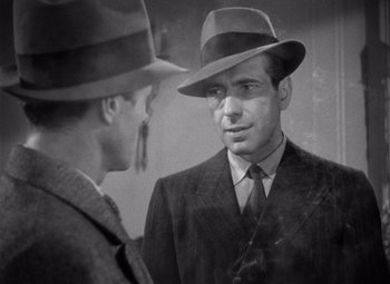 Movie still from “The Maltese Falcon” (1941), directed by John Huston – A man in a suit and a hat talking to another man in a suit and a hat; Close Up shot, Over the shoulder angle