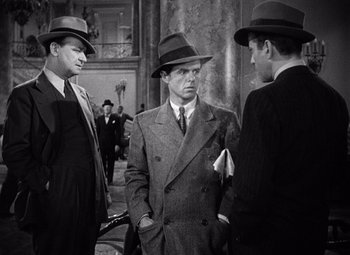 Movie still from “The Maltese Falcon” (1941), directed by John Huston – A group of men standing next to each other wearing hats; Medium shot, Over the shoulder angle