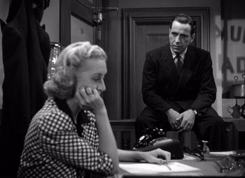 Movie still from “The Maltese Falcon” (1941), directed by John Huston – A man and a woman sitting at a table; Medium shot, Over the shoulder angle