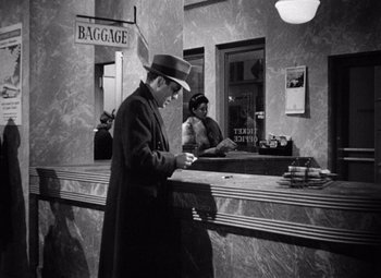 Movie still from “The Maltese Falcon” (1941), directed by John Huston – A black and white photo of a man and a woman at a counter; Medium shot, High angle