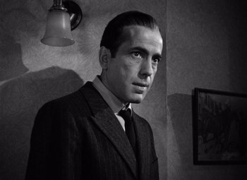Movie still from “The Maltese Falcon” (1941), directed by John Huston – Black and white photograph of a man wearing a suit and tie; Close Up shot, Low angle
