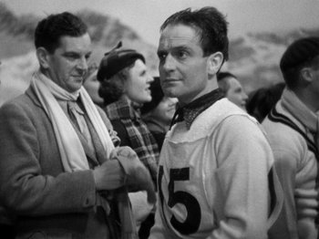 Movie still from “The Man Who Knew Too Much” (1934), directed by Alfred Hitchcock – A black and white photo of a man in a crowd of people; Medium shot, Low angle