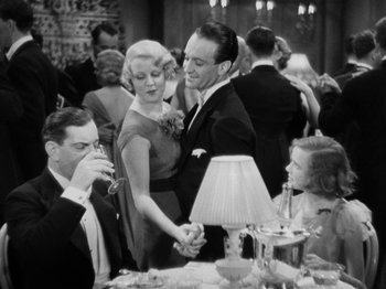 Movie still from “The Man Who Knew Too Much” (1934), directed by Alfred Hitchcock – A man and a woman holding hands at a party; Medium shot, High angle