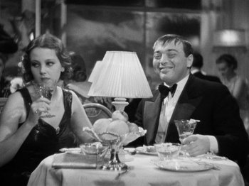 Movie still from “The Man Who Knew Too Much” (1934), directed by Alfred Hitchcock – A man and a woman sitting at a dinner table; Medium shot, High angle