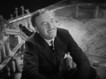Movie still from “The Man Who Knew Too Much” (1934), directed by Alfred Hitchcock – An old photo of a man in a suit and tie smiling; Close Up shot, High angle