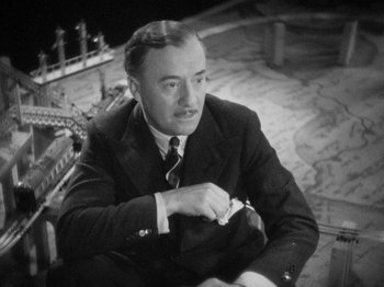 Movie still from “The Man Who Knew Too Much” (1934), directed by Alfred Hitchcock – An old black and white photo of a man in a suit and tie; Close Up shot, High angle