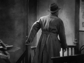 Movie still from “The Man Who Knew Too Much” (1934), directed by Alfred Hitchcock – An older man in a trench coat and a hat; Medium shot, Low angle