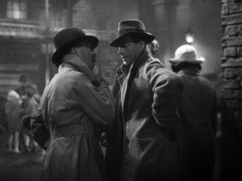 Movie still from “The Man Who Knew Too Much” (1934), directed by Alfred Hitchcock – A black and white photo of two men talking to each other; Medium shot, Over the shoulder angle