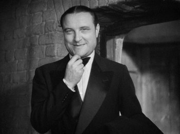 Movie still from “The Man Who Knew Too Much” (1934), directed by Alfred Hitchcock – A black and white photo of a man in a tuxedo; Close Up shot, Low angle