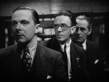 Movie still from “The Man Who Knew Too Much” (1934), directed by Alfred Hitchcock – A group of three men in suits and ties; Close Up shot, Low angle