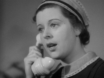 Movie still from “The Man Who Knew Too Much” (1934), directed by Alfred Hitchcock – A woman talking on a phone while wearing a hat; Close Up shot, High angle
