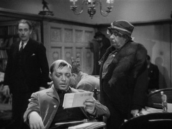 Movie still from “The Man Who Knew Too Much” (1934), directed by Alfred Hitchcock – An old photo of a man and a woman looking at a piece of paper; Medium shot, Over the shoulder angle