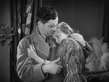 Movie still from “The Man Who Knew Too Much” (1934), directed by Alfred Hitchcock – A man and a woman embracing each other in front of a curtain; Medium shot, High angle